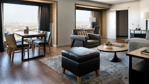 A modern hotel room with a dining area, two seating areas, and a view of the city. - Oakland Marriott City Center (Oakland)