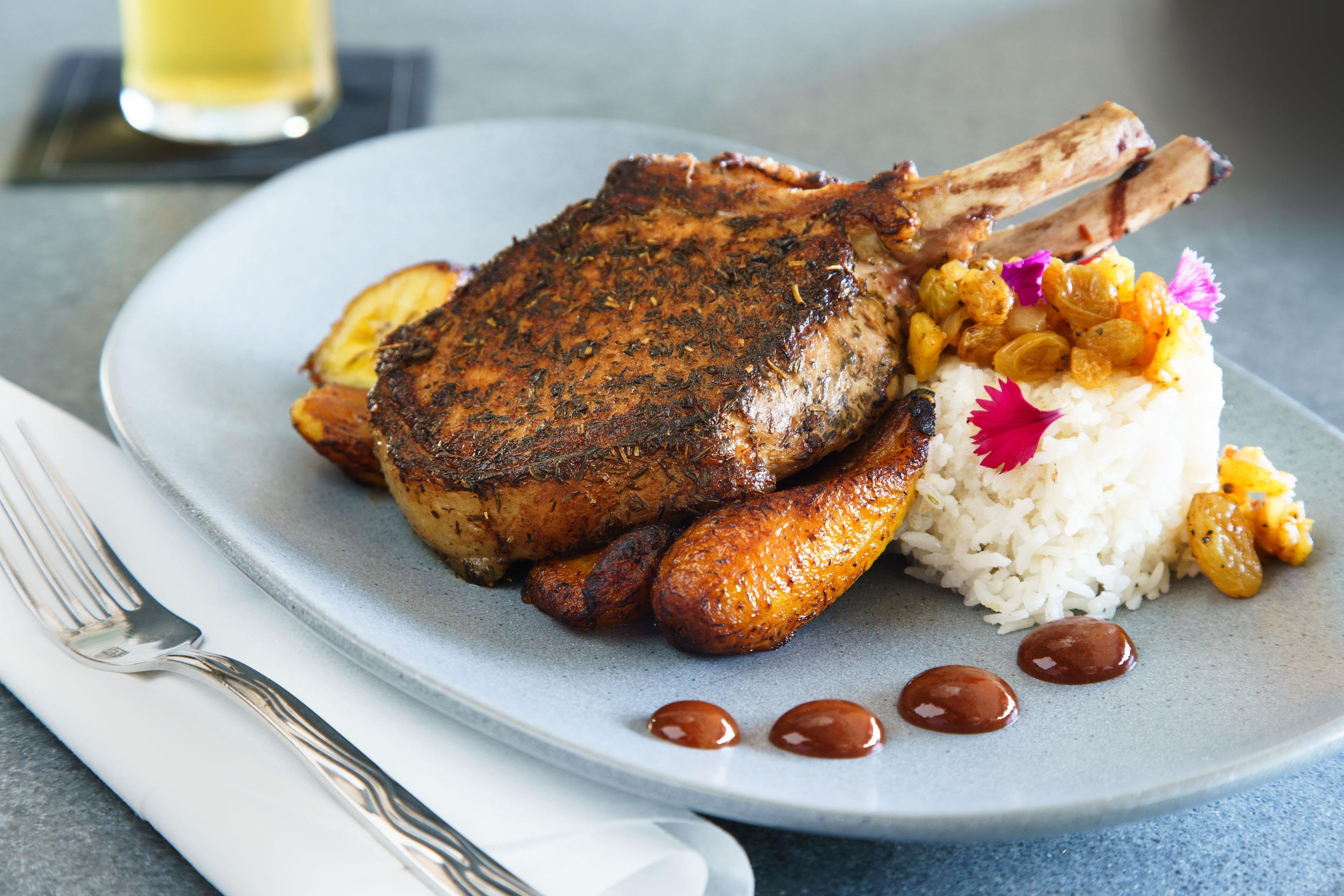 Un plato con carne a la parrilla, papas, arroz y una salsa.