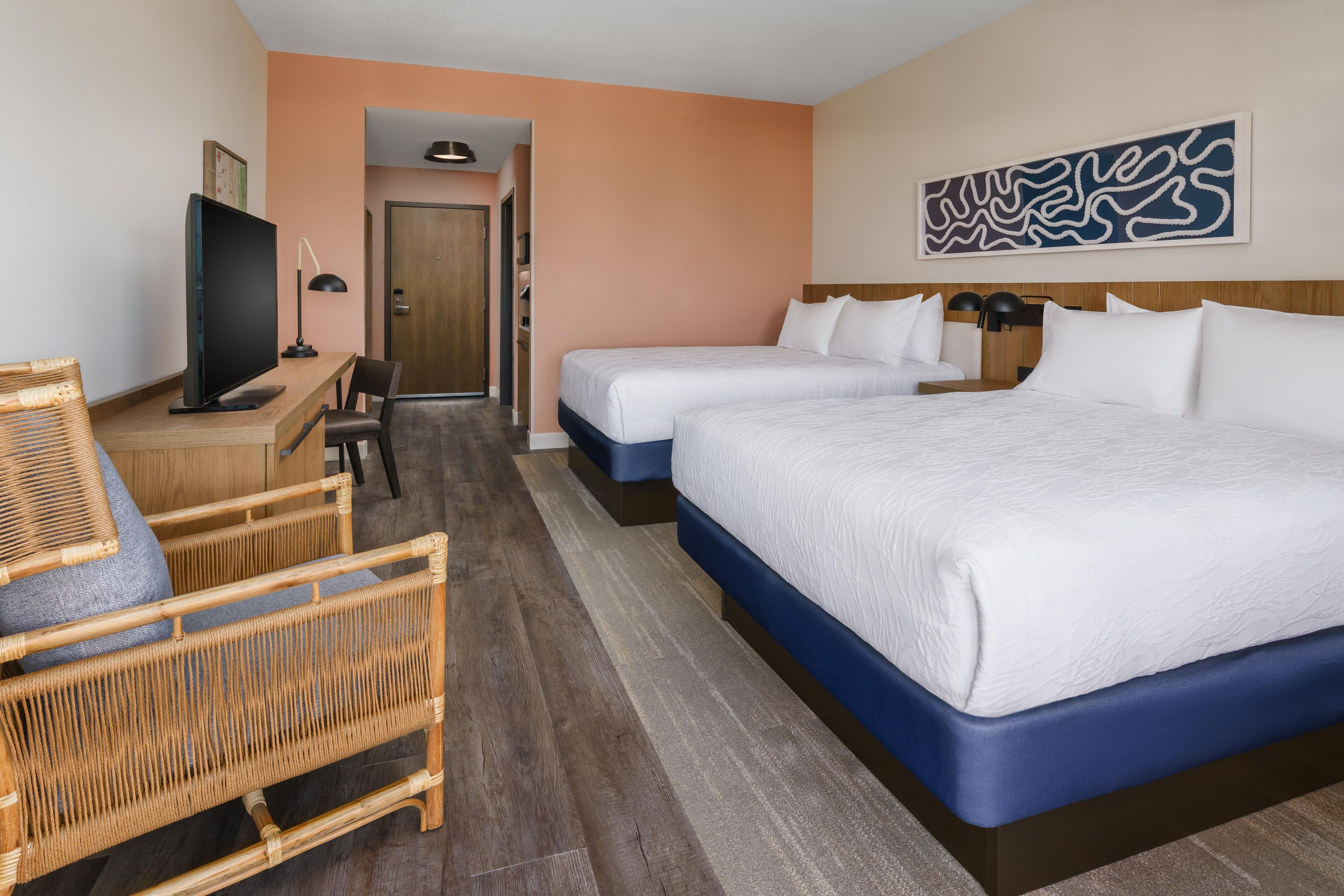 Una habitación de hotel con una cama grande, un escritorio con computadora, una silla y televisión.