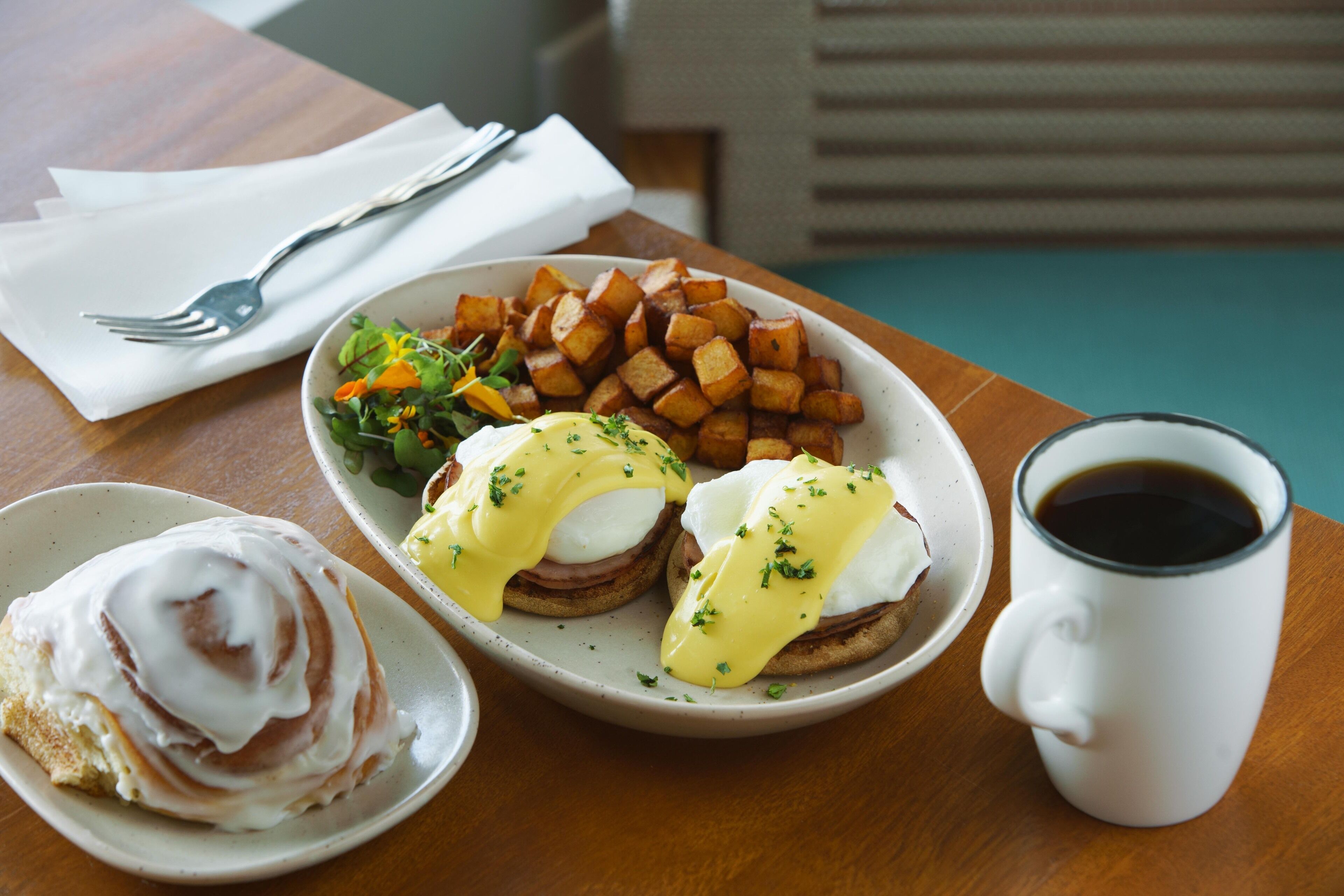 Ein Frühstücksteller mit Eggs Benedict, Rösti und einem kleinen Salat.