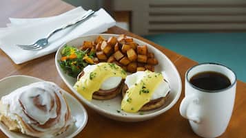 A breakfast plate with eggs benedict, hash browns, and a side salad.