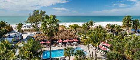 A resort with a pool, beach, and palm trees.