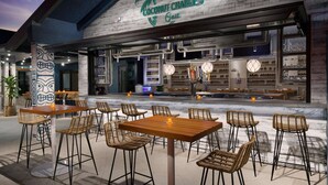 Un espace extérieur aménagé avec des chaises et des tables en osier, situé dans un restaurant appelé Coconut Charlie's Grill.