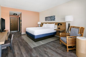 Une chambre d’hôtel avec un lit, un bureau, une chaise, une télévision et une porte.