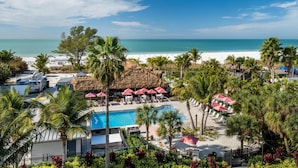 Un complexe hôtelier doté d’une piscine, d’une plage et de palmiers.