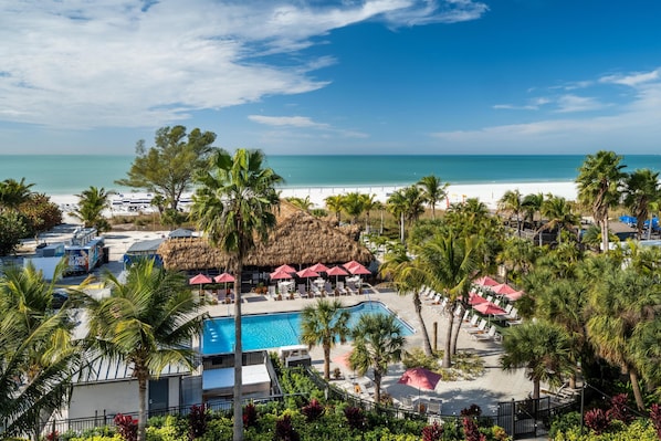 Un complexe hôtelier doté d’une piscine, d’une plage et de palmiers.