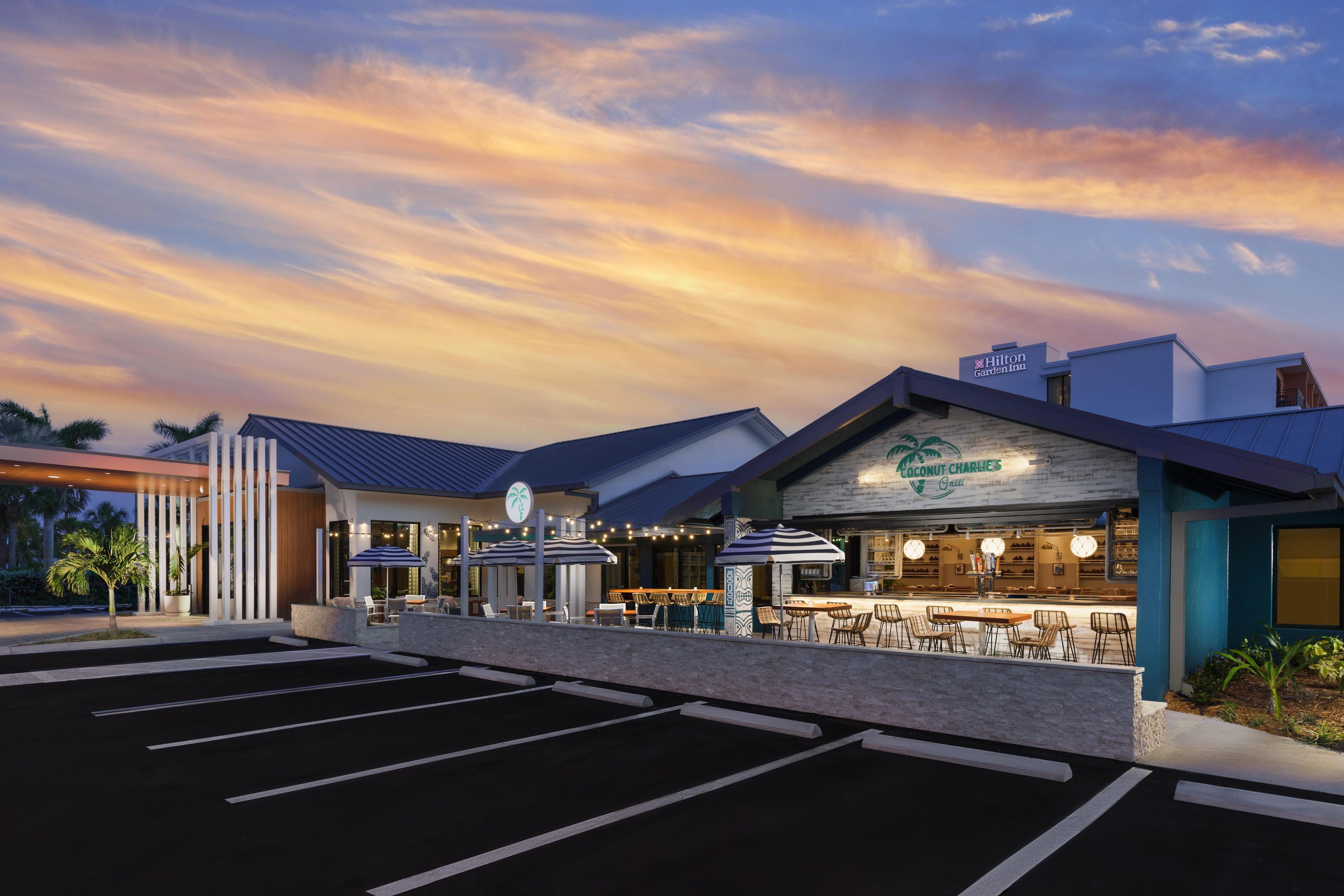 A hotel with a modern design, outdoor seating area, and a parking lot.