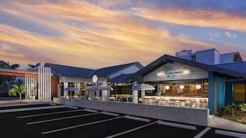 A hotel with a modern design, outdoor seating area, and a parking lot.