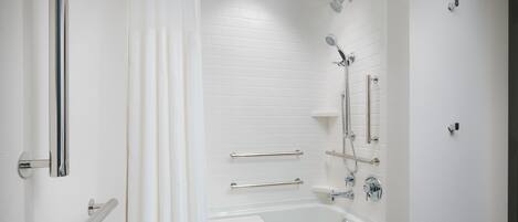 A modern bathroom with a white bathtub, a shower with a handheld showerhead, and a glass shower door.