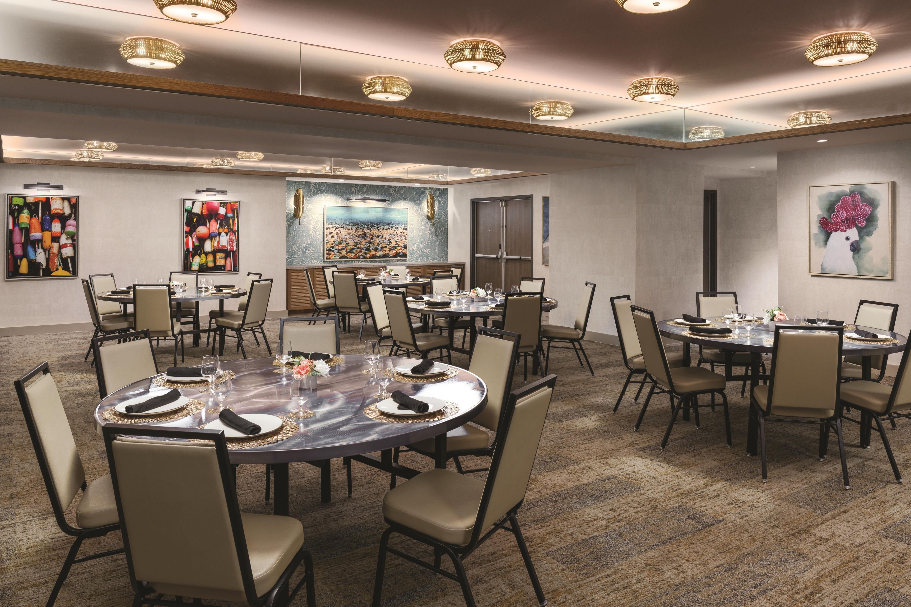 A conference room with round tables, chairs, and artwork on the walls.