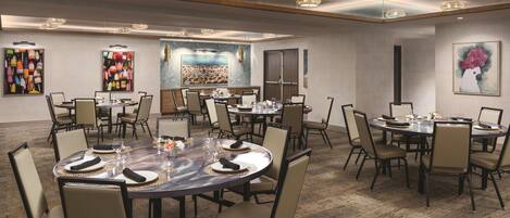 A conference room with round tables, chairs, and artwork on the walls.