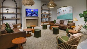 Un espace de détente moderne avec des canapés en cuir, des tables rondes en bois et des fauteuils en osier.