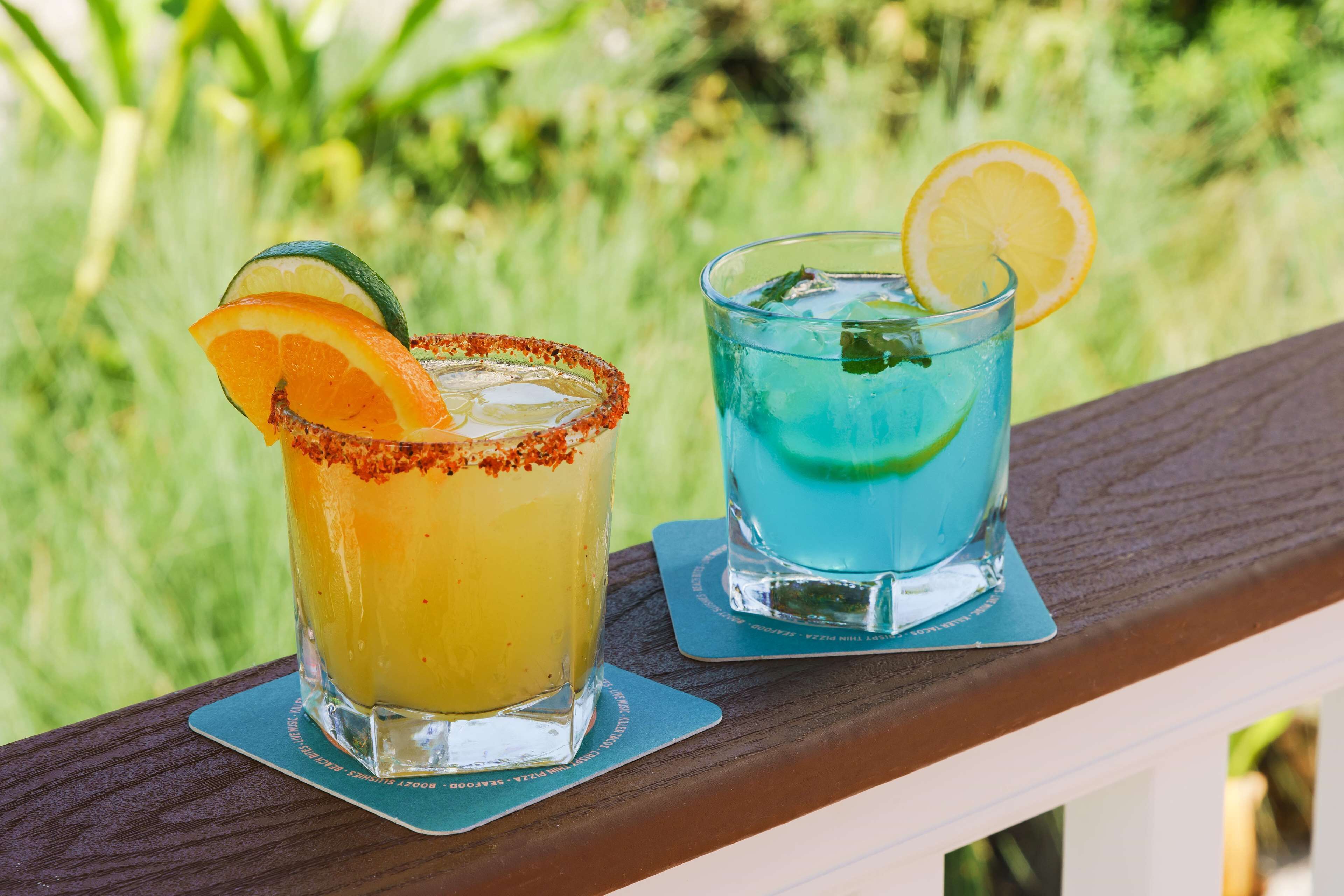 Dos bebidas sobre una cubierta de madera, con un fondo verde desenfocado.
