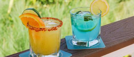 Dos bebidas sobre una cubierta de madera, con un fondo verde desenfocado.