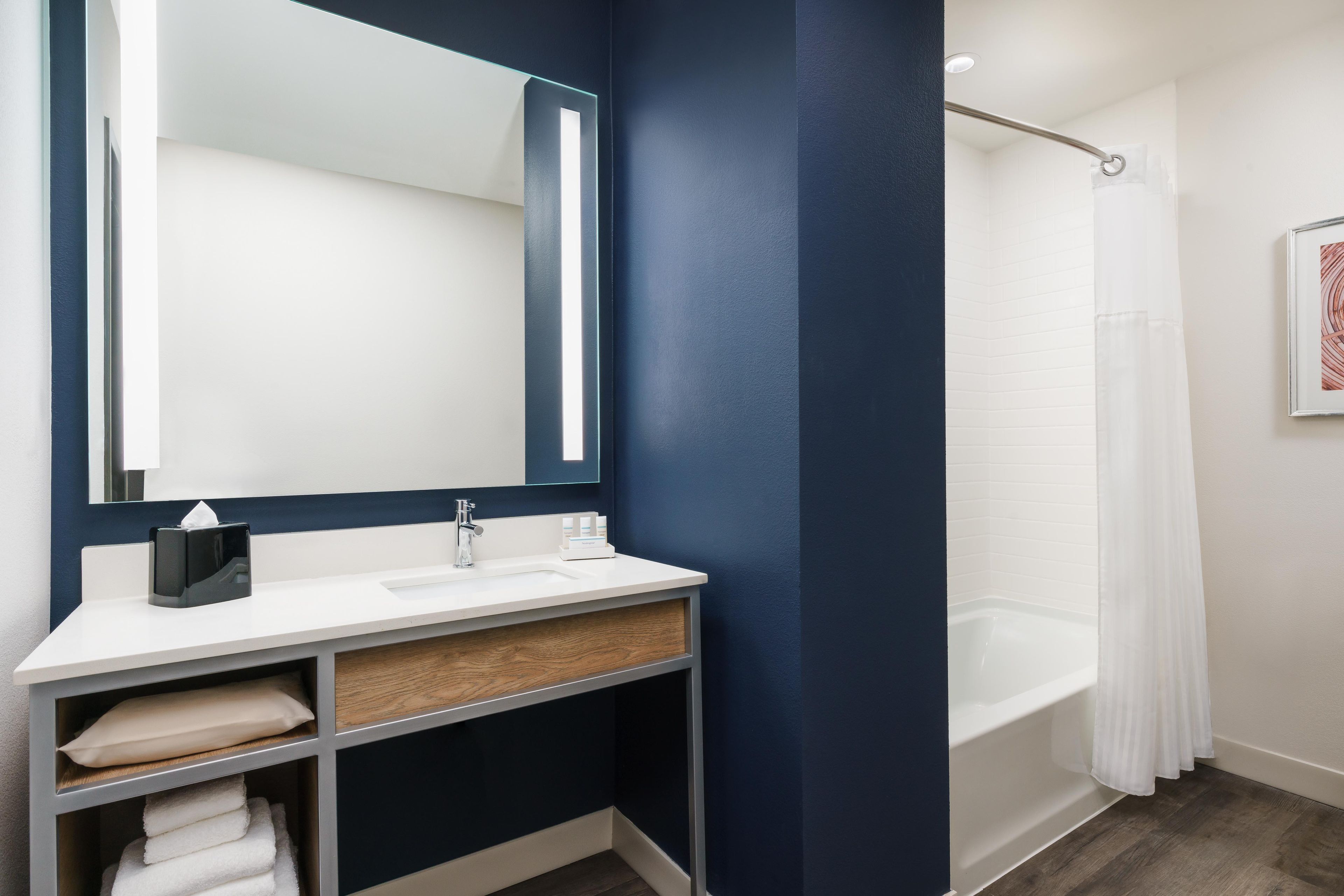 A modern bathroom with a white sink, a mirror, a towel rack, and a bathtub.