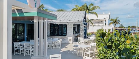 Un restaurante con terraza, palmeras y cielo despejado.