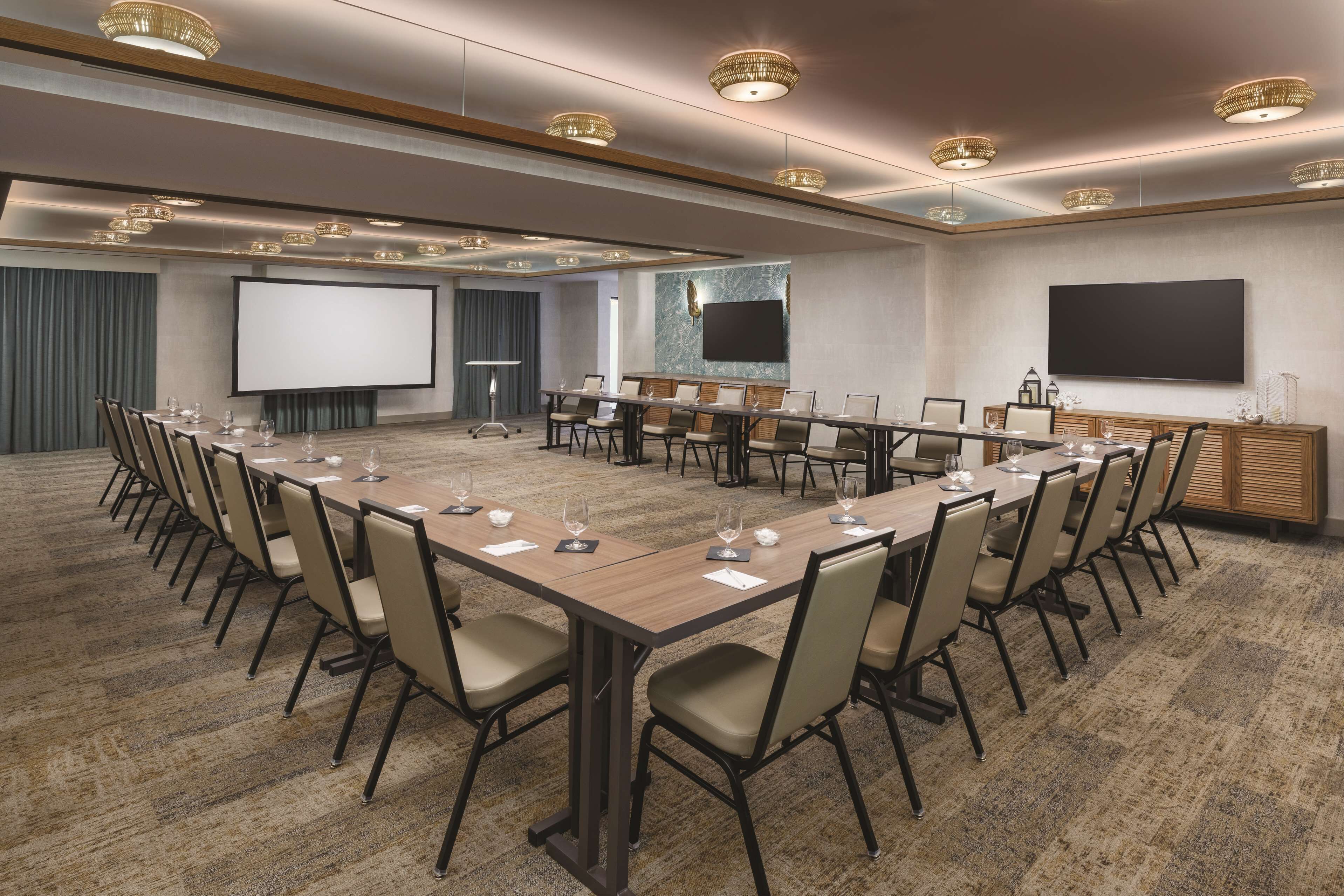 A conference room with a long table, chairs, a projector screen, and a large flat-screen TV.