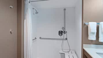 Ducha con cabezal de ducha de mano, un accesorio de ducha manual y un perchero con toallas.