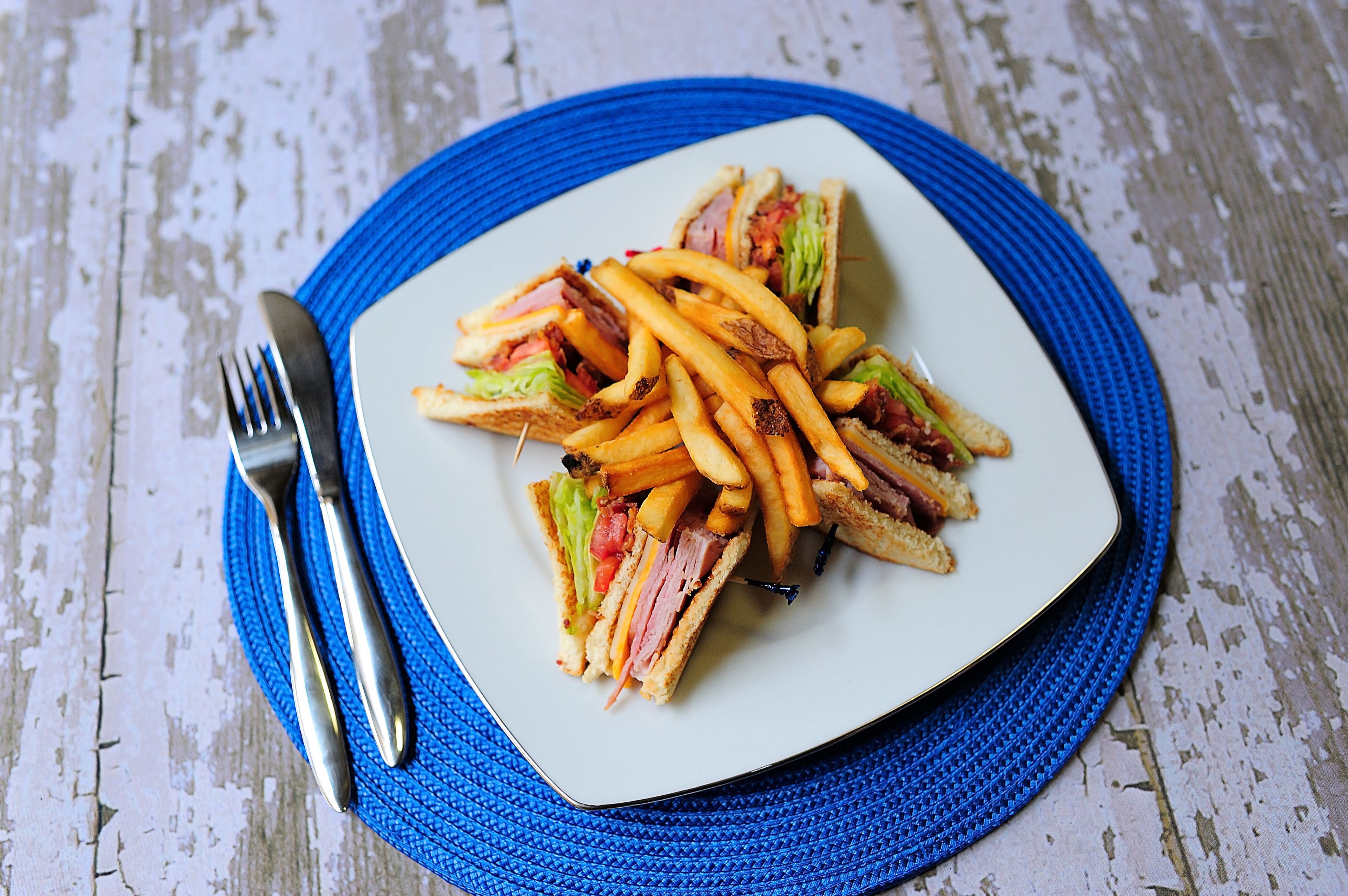 Un plato de sándwiches y papas fritas sobre un camino de mesa azul.