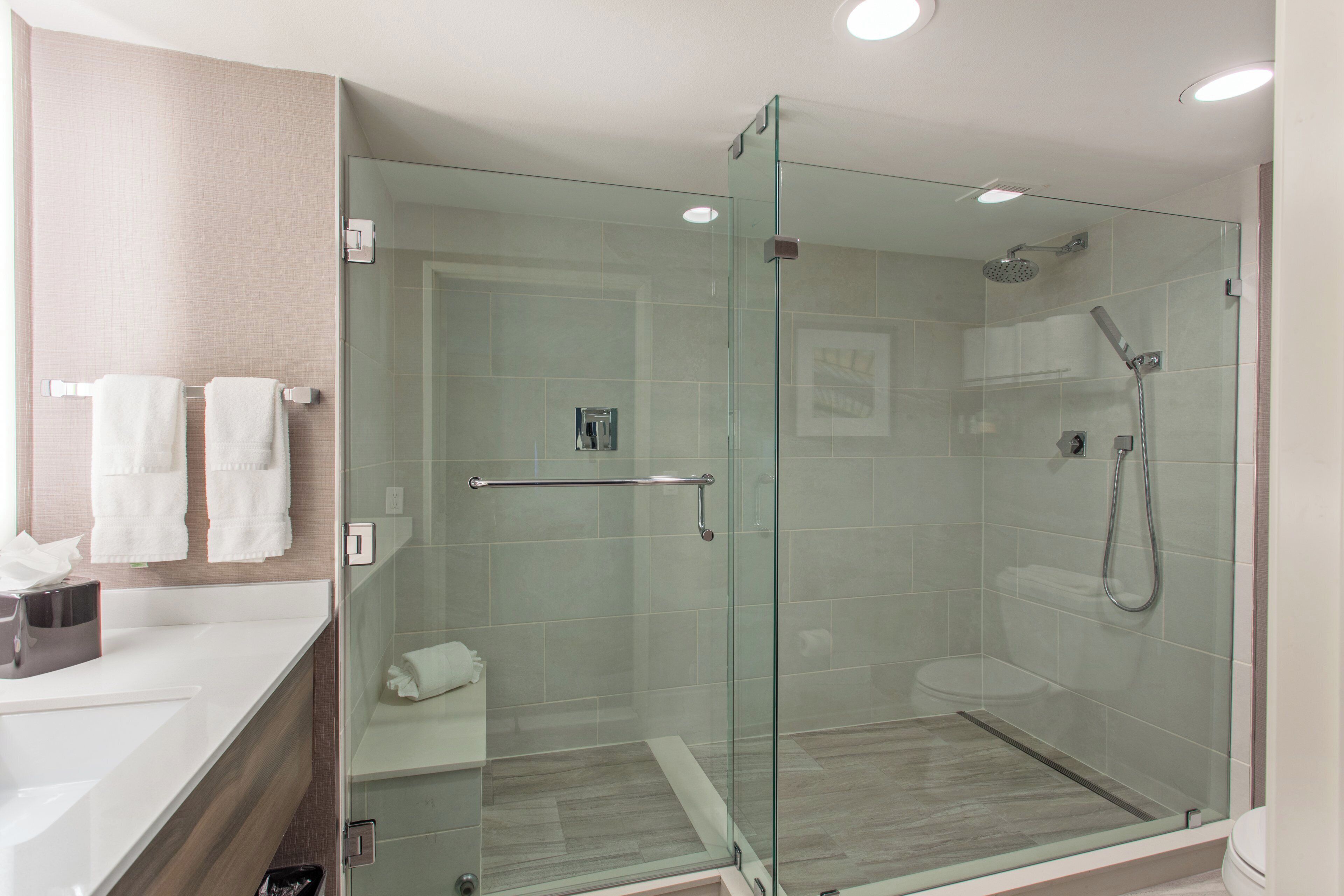 A modern bathroom with a glass-enclosed shower, a white sink, and a towel rack.