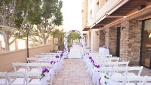 Une allée pour cérémonie de mariage en plein air, avec des chaises blanches et des décorations florales.