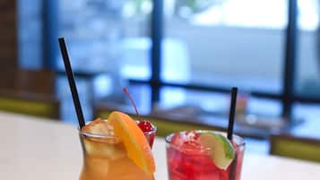 Deux cocktails sur une table en marbre, avec un arrière-plan flou représentant une fenêtre et l’intérieur d’une pièce.