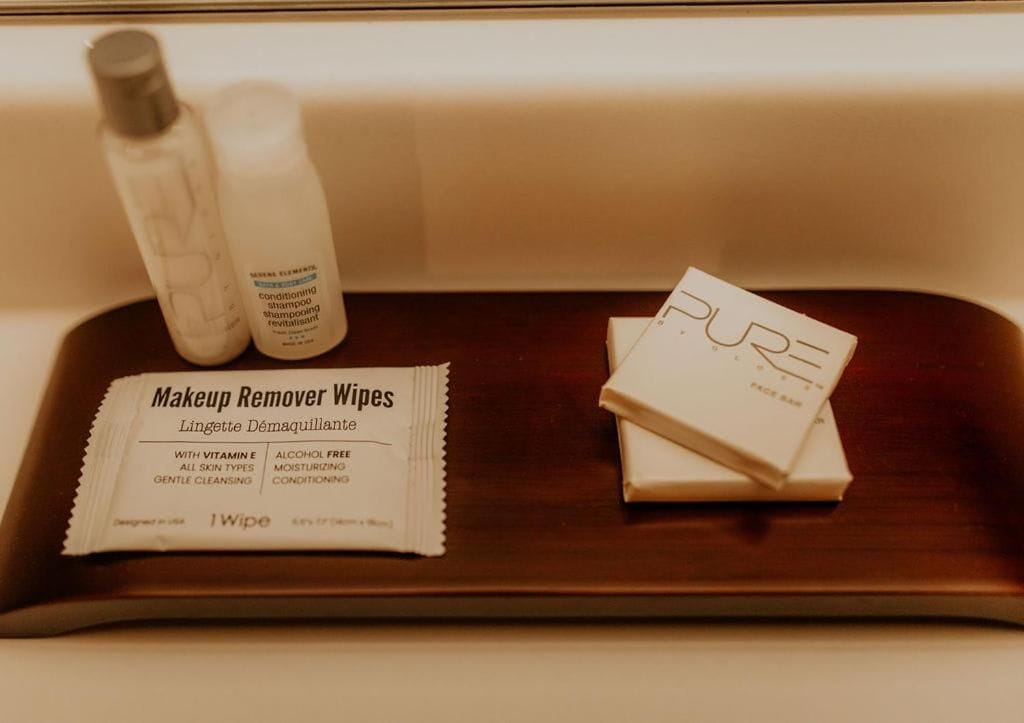 A tray with makeup remover wipes, a bottle of shampoo, and a bar of soap.