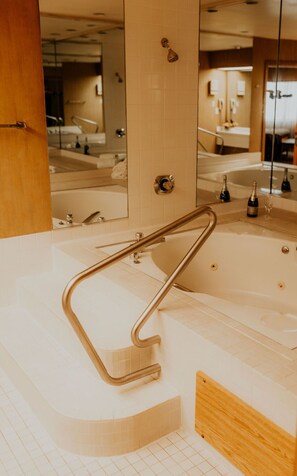 A modern bathroom with a large bathtub, a glass shower enclosure, and a wooden vanity.