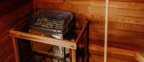 Una cabaña de madera con un cartel que indica sauna de secado, un letrero de precaución y un estante de metal con objetos.