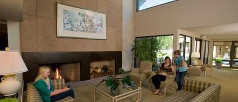 A lobby with a fireplace, seating area, and a large window.