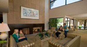 A lobby with a fireplace, seating area, and a large window.