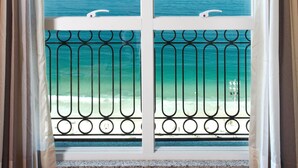 Una ventana con vista al océano y un balcón con barandilla de metal.