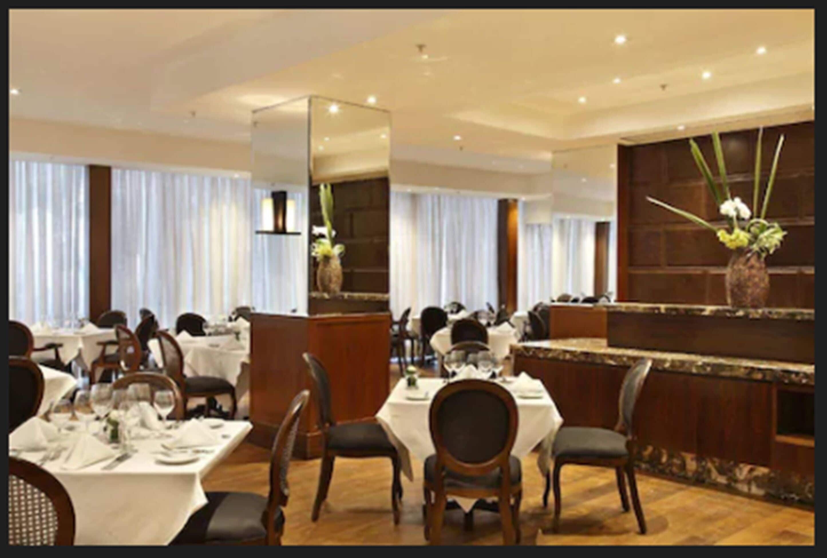 Un restaurante con mesas redondas, sillas y una zona de bar.