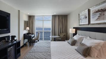 Une chambre d’hôtel avec un grand lit, un bureau, une chaise, une télévision et un balcon avec vue.
