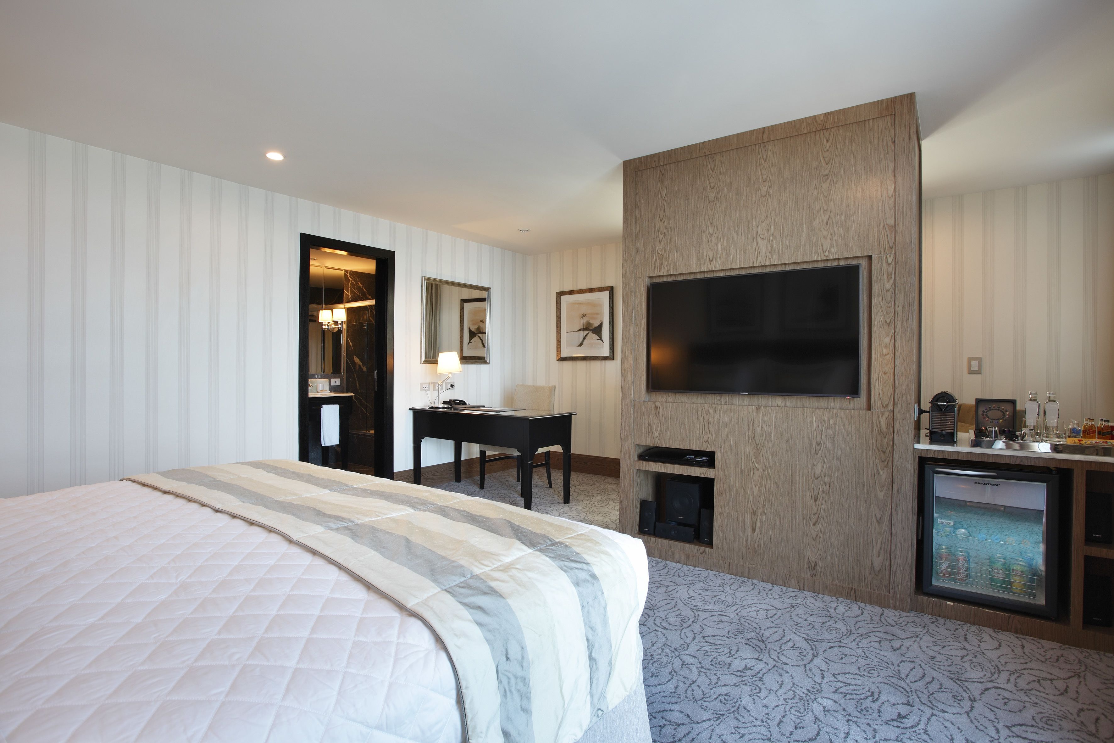 Une chambre d’hôtel avec un grand lit, un bureau, une télévision et un minibar.