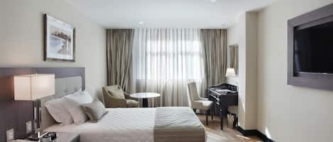 Habitación de hotel con dos camas, un escritorio con silla, una mesita y un televisor.