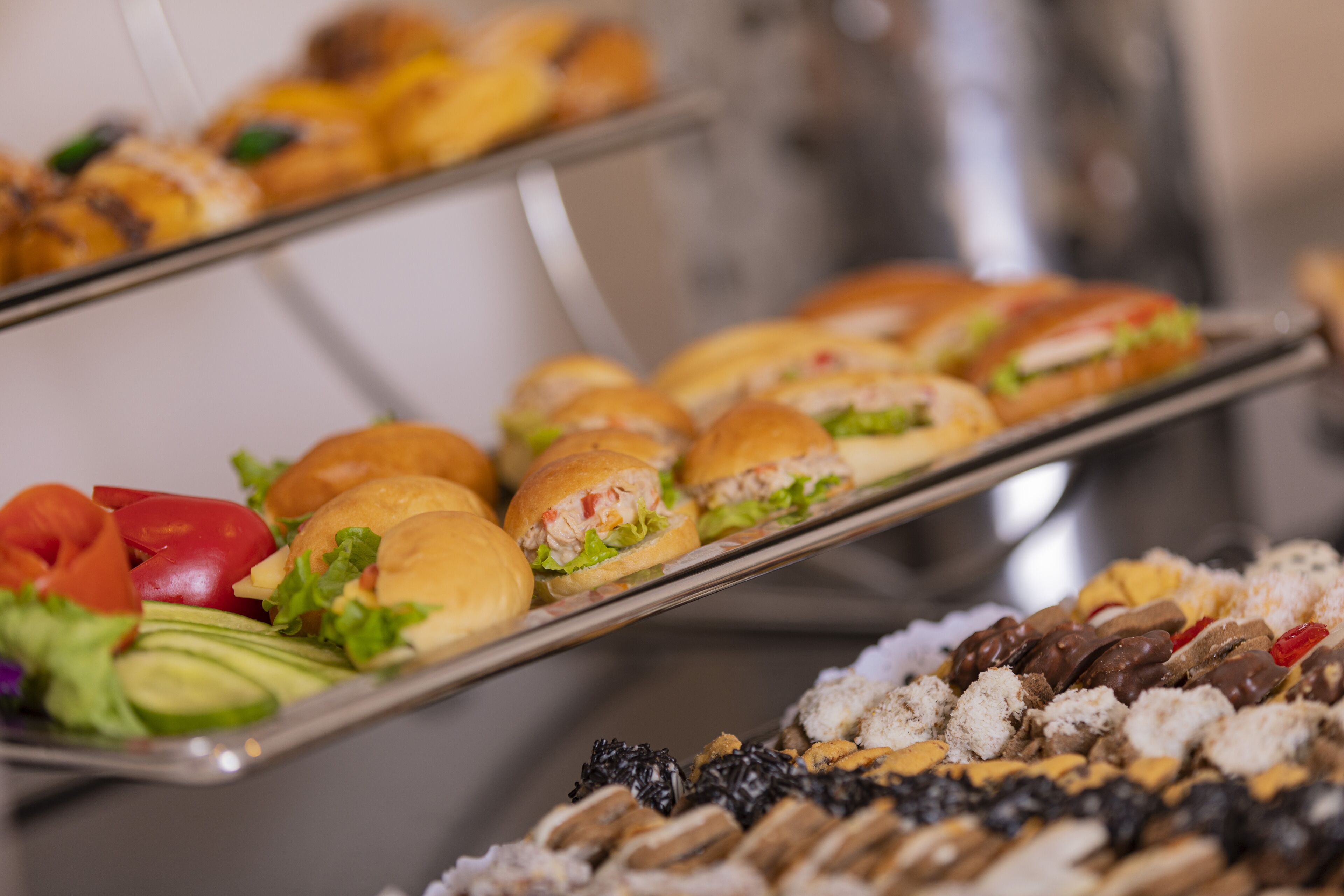 Ein reichhaltiges Buffet mit verschiedenen Speisen, darunter Sandwiches, Salate und Desserts.
