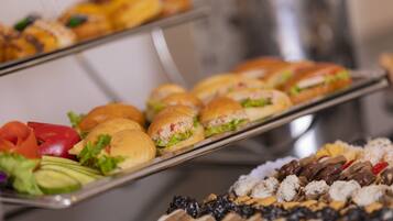 Ein reichhaltiges Buffet mit verschiedenen Speisen, darunter Sandwiches, Salate und Desserts.