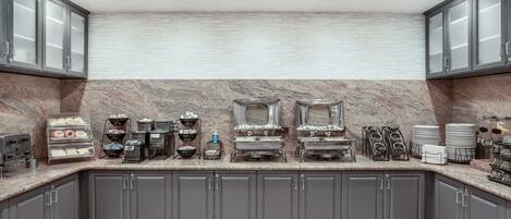 A kitchen with granite countertops, grey cabinets, and a marble backsplash.