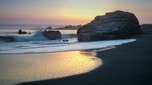 A beach with large rocks and waves at sunset. - Beachfront Inn (Brookings)