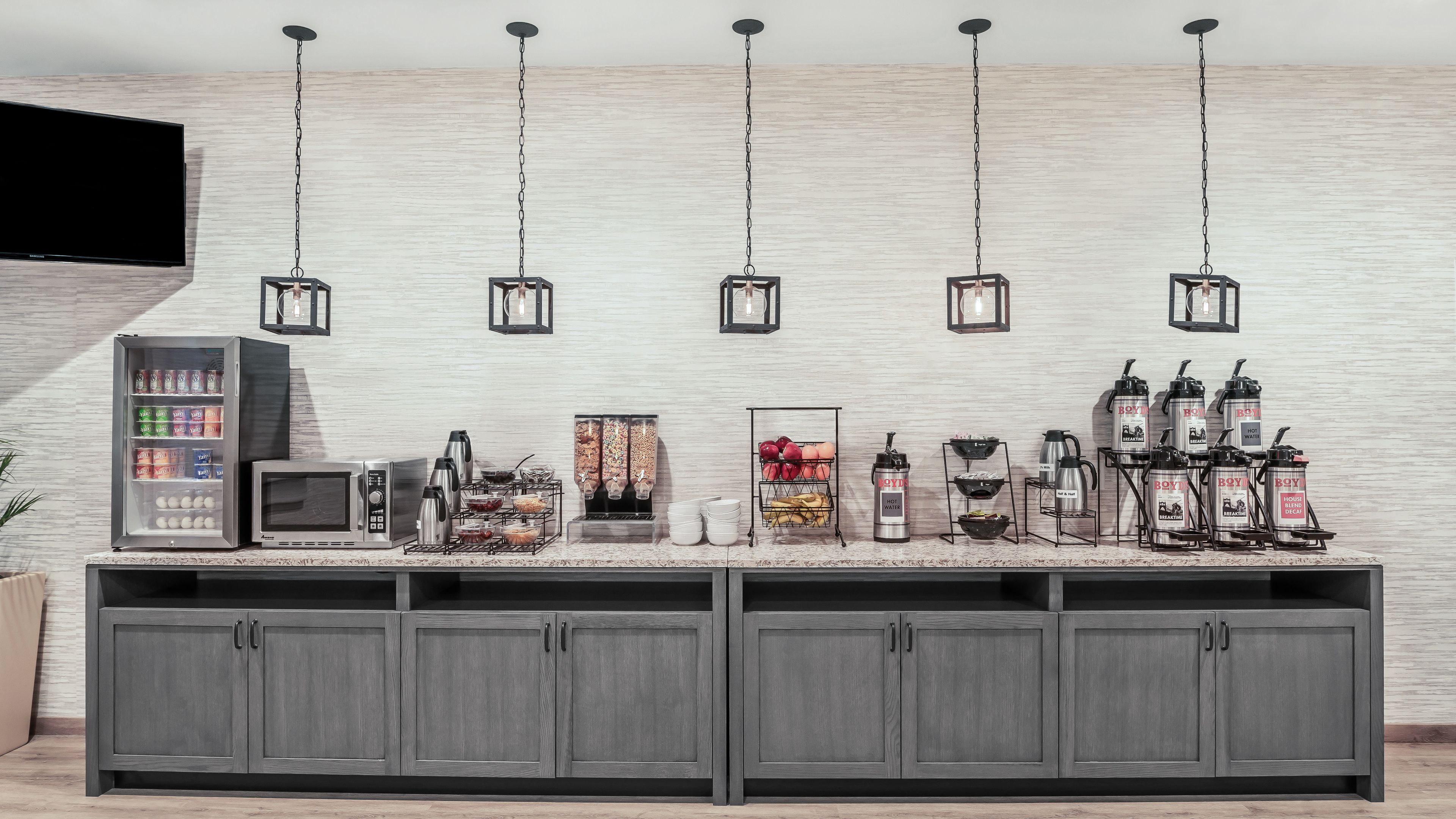 Een moderne keuken met een inbouwkoelkast, magnetron en koffiehoek.