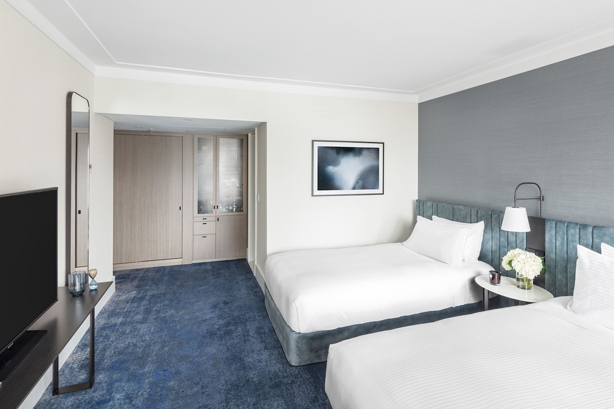 A hotel room with two beds, a TV, a desk, and a wardrobe.