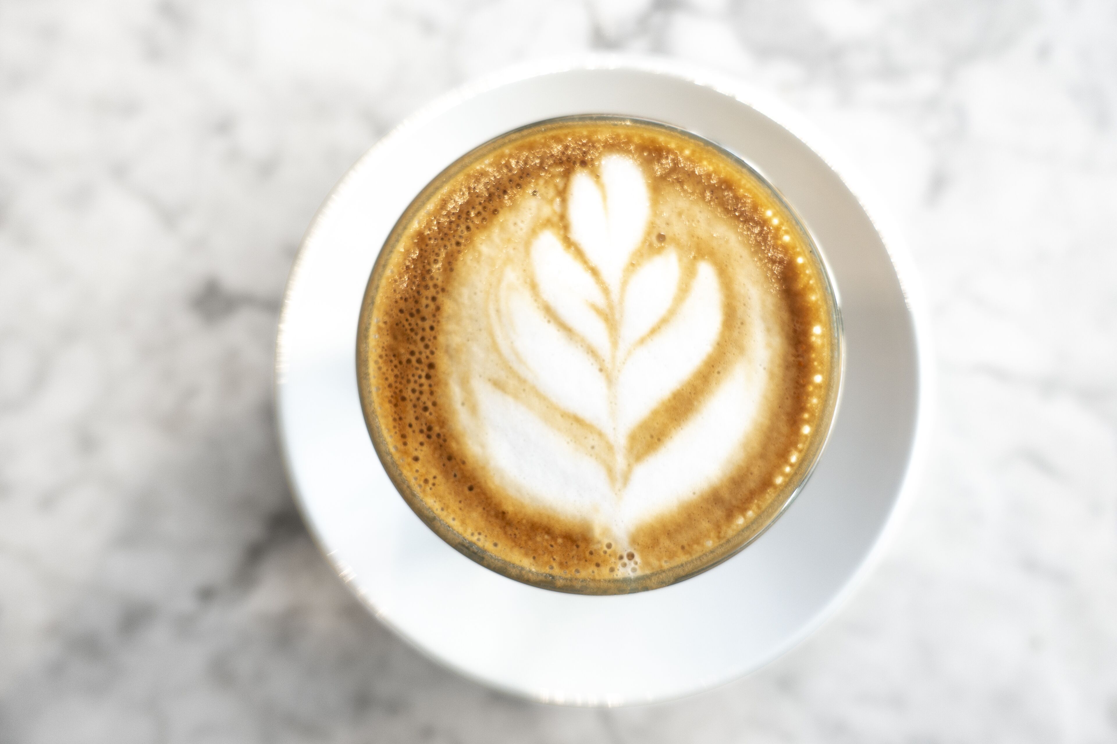 Uma chávena de café com arte de latte sobre um prato branco.