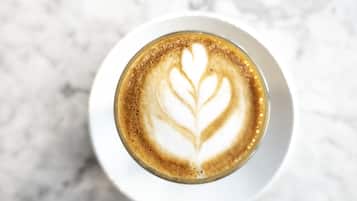 Uma chávena de café com arte de latte sobre um prato branco.