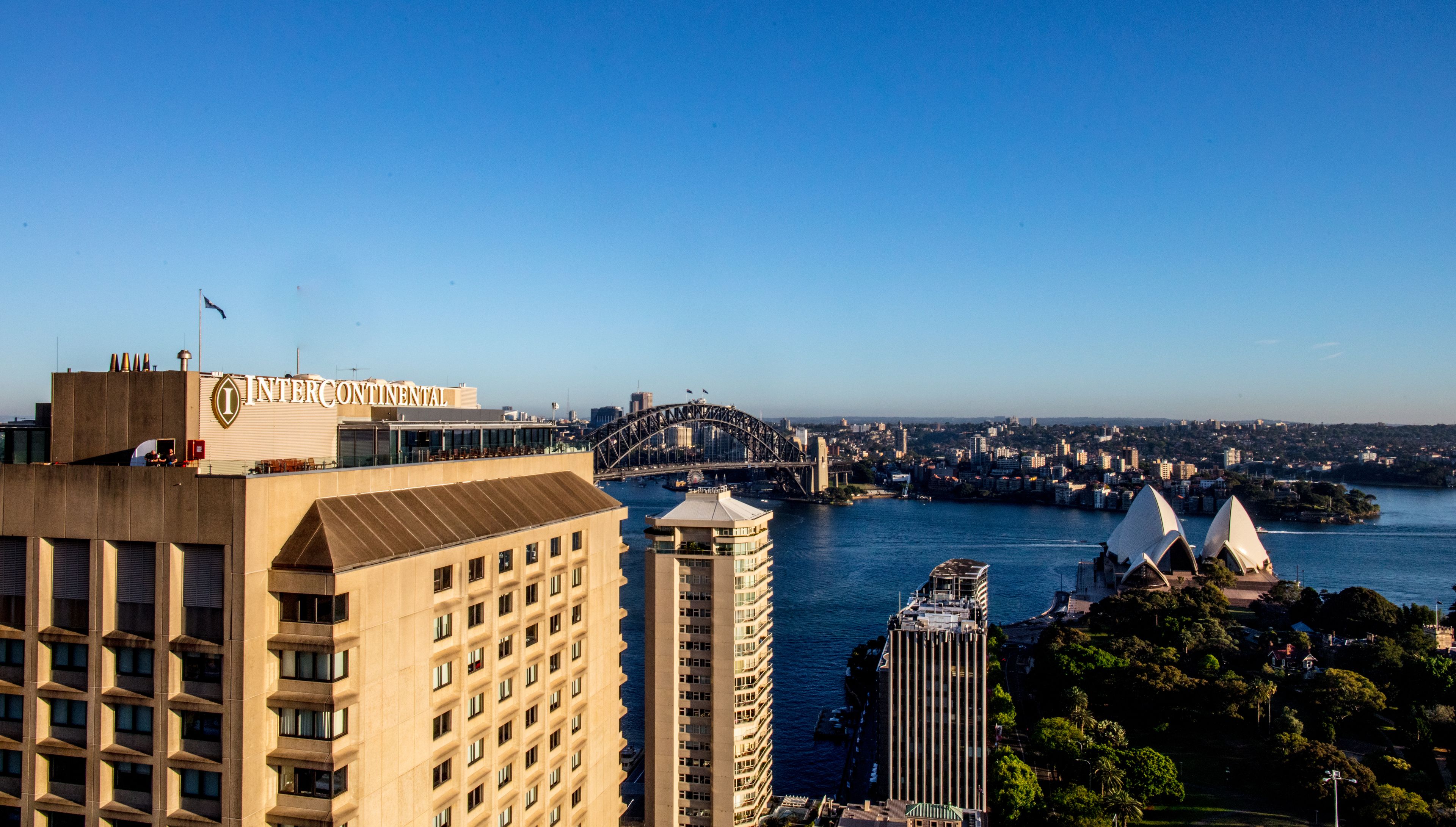 A high-rise hotel with a view of the Sydney Opera House and Harbour Bridge.