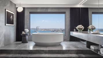 Un baño moderno con una bañera grande, vistas de la ciudad y suelo de mármol.
