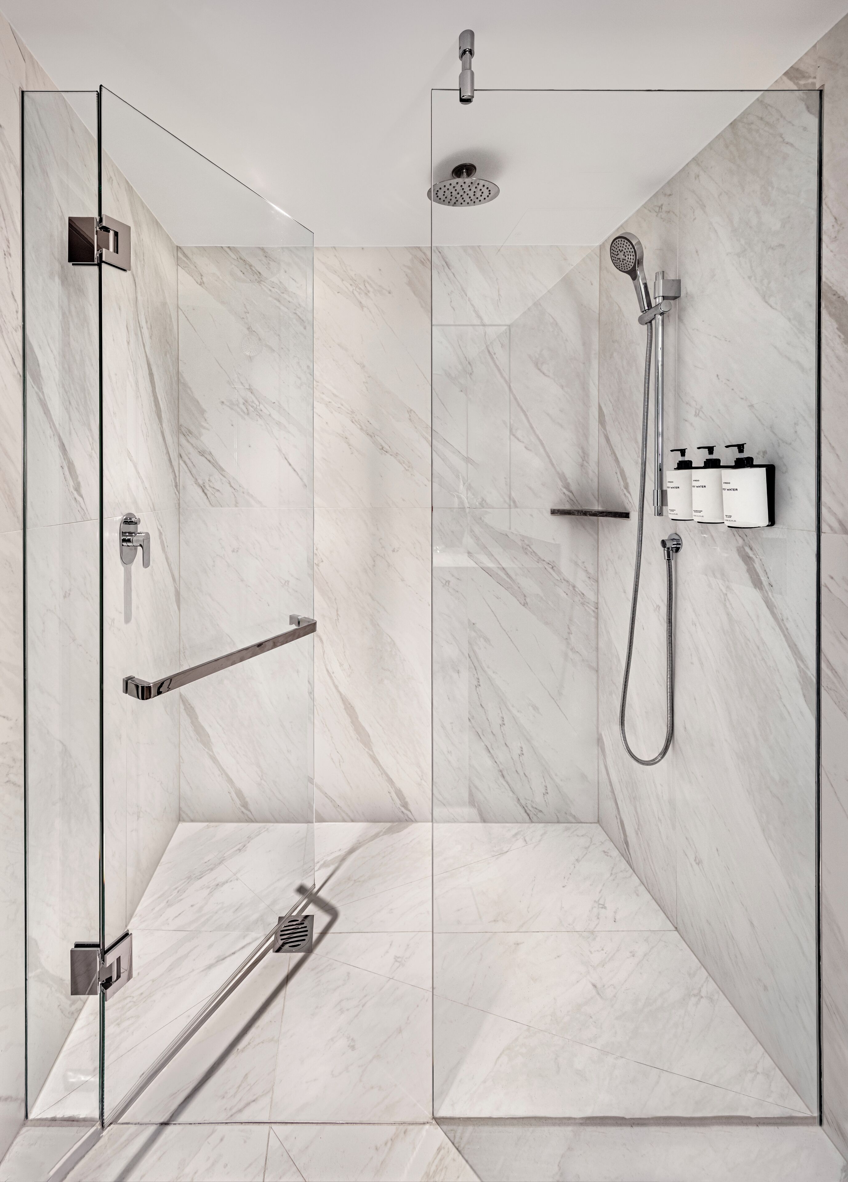 A modern shower with a glass enclosure, a handheld showerhead, and a wall-mounted faucet.