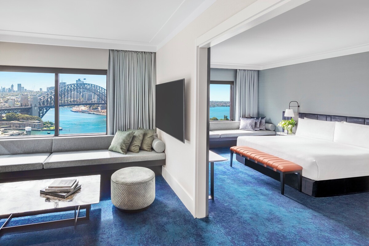 A hotel room with a large window offering a view of a bridge and cityscape.