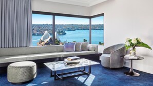 A modern living room with a large window offering a cityscape view, a sofa, a coffee table, and a chair. - InterContinental Sydney by IHG (Sydney)
