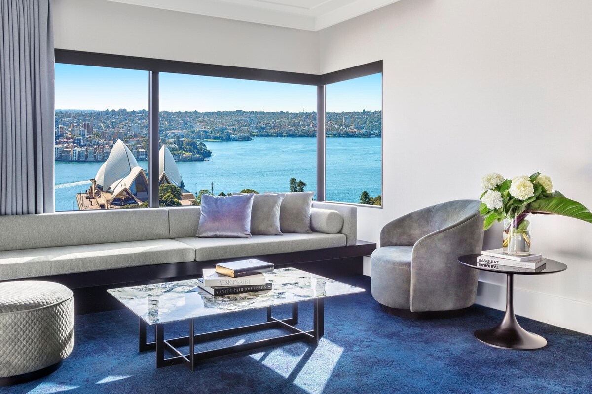A modern living room with a large window offering a cityscape view, a sofa, a coffee table, and a chair.